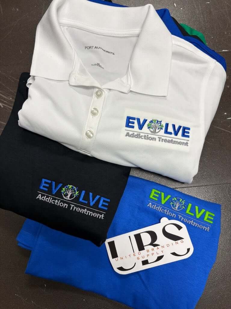 White, black, and blue polos embroidered with the Evolve Addiction Treatment logo, by United Branding Supply.