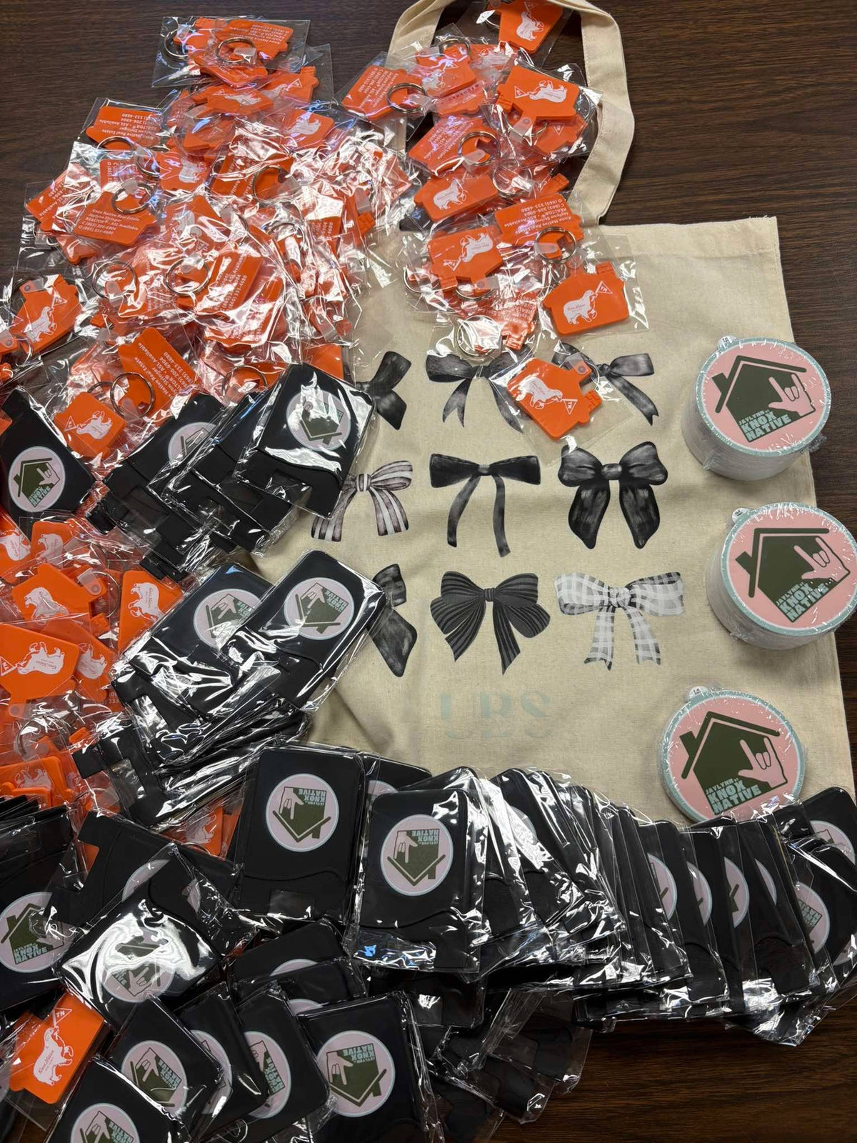 Full display of custom Knox Native Real Estate keychains, round "Jaylynn at Knox Native" stickers, and a branded tote bag, by United Branding Supply