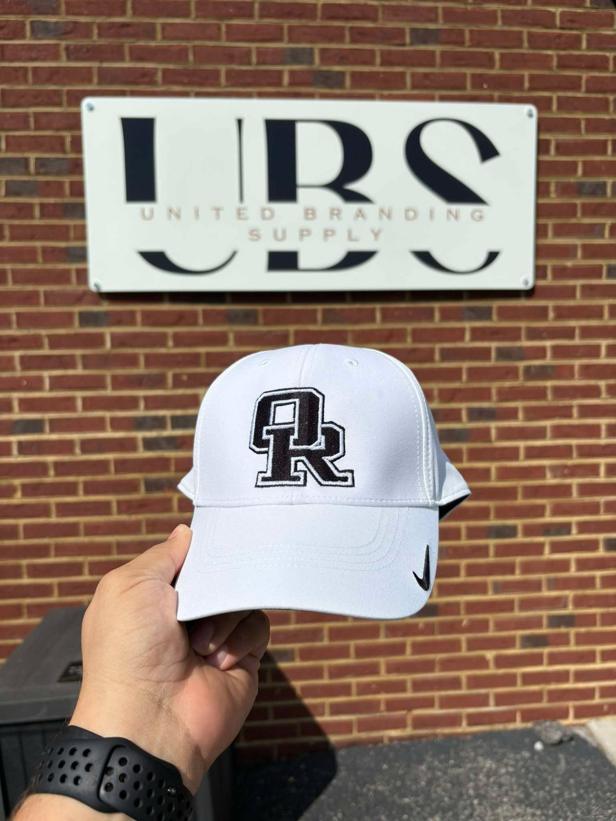 White cap embroidered with a bold 'OR' logo for Oak Ridge, by United Branding Supply.